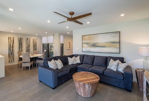 A modern living room with a sectional sofa, a round coffee table, and a ceiling fan.