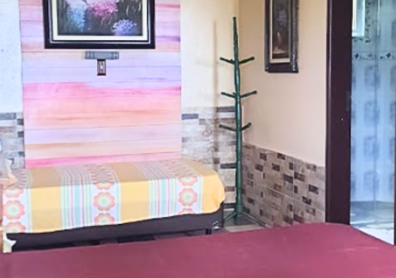 Una habitación con una cama, un perchero verde y una pared con un diseño colorido.