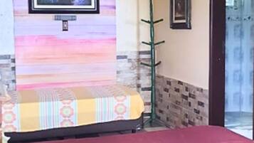 Una habitación con una cama, un perchero verde y una pared con un diseño colorido.