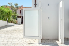A white building with a closed door, a small window, and a metal handle.