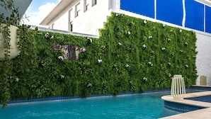 A swimming pool with a green vertical garden wall and a decorative sign.