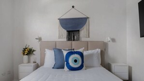 A neatly arranged bedroom with a bed, two bedside tables, a wall-mounted hanging, and a small vase with flowers.
