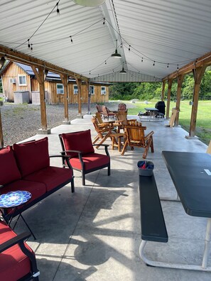 An outdoor covered patio with wooden furniture, a table, and string lights.