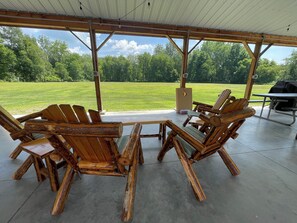 An outdoor seating area with rustic wooden furniture and a view of a grassy field.