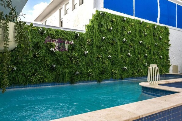 A swimming pool with a green vertical garden wall and a decorative sign.