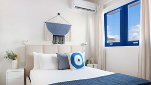 Ein Hotelzimmer mit einem Bett, einem Wandbehang aus Makramee, einem Fenster mit Vorhängen und einem Nachttisch mit einer Pflanze.