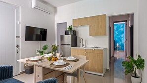 Eine moderne Küche mit integriertem Mikrowellenherd, Kühlschrank und Spüle. Ein Esstisch ist gedeckt mit Tellern, Gläsern und einer Obstschale.