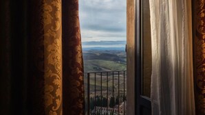 A balcony with a view of rolling hills and a distant building. - Bellarmino Boutique Apartments (Montepulciano)