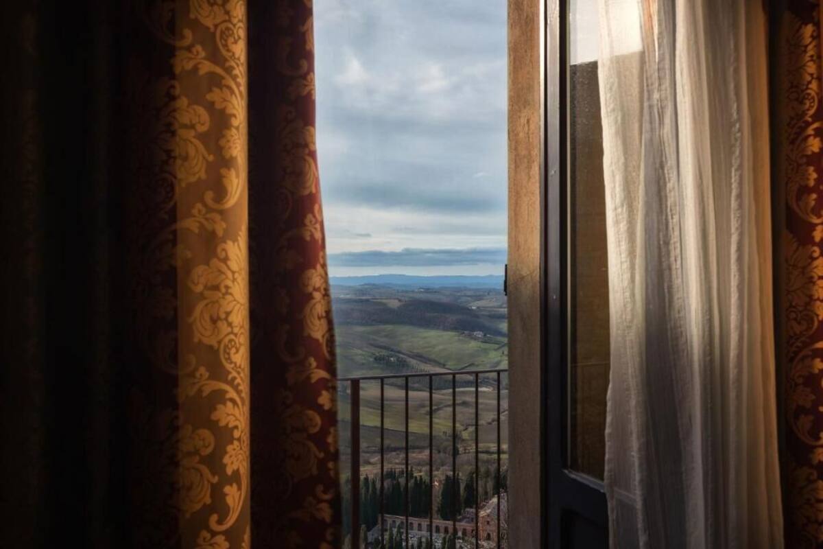 A balcony with a view of rolling hills and a distant building.