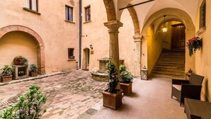 A courtyard with stone flooring, arches, and potted plants. - Bellarmino Boutique Apartments (Montepulciano)