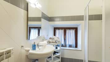 Ein Badezimmer mit Waschbecken, Spiegel, Dusche und einem Fenster mit Vorhängen.