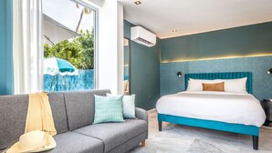 A modern hotel room with a large bed, a grey sofa, and a view of the outdoors.