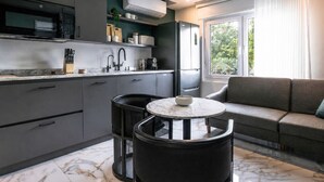 Een moderne keuken met een inbouwmagnetron, een koelkast en een eethoek met een ronde tafel en twee stoelen.