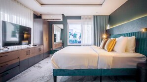 Een moderne hotelkamer met een groot bed, een televisie, een badkamer en uitzicht op het omliggende landschap.