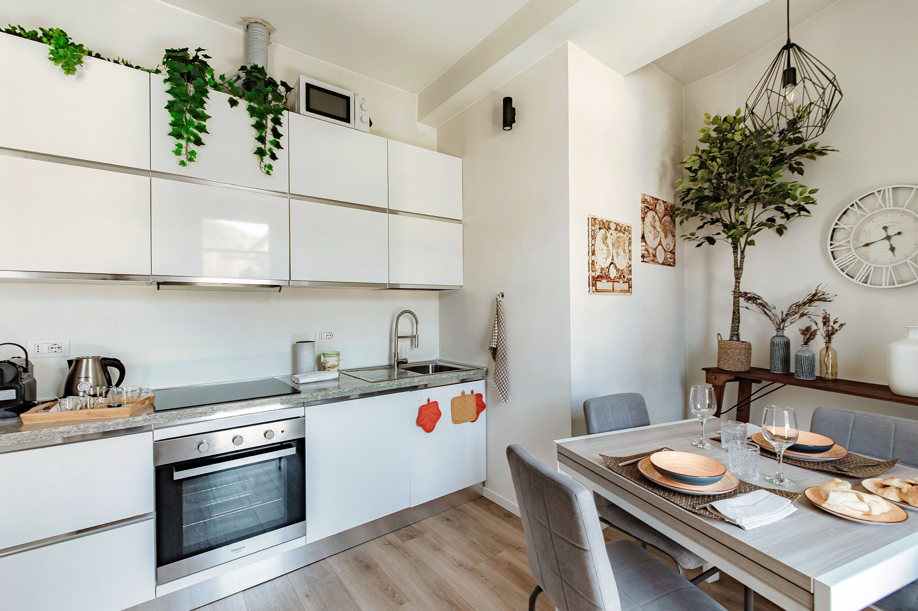 A modern kitchen with white cabinets, a built-in oven, and a dining area with a table set for two.