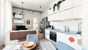 A modern kitchen with white cabinets, a built-in oven, and a stainless steel refrigerator. - Nest & Rest (Como)