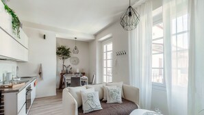 A modern kitchen with a dining area, a sofa with decorative pillows, and a dining table with glasses. - Nest & Rest (Como)