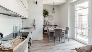 A modern kitchen with a dining area, large windows, and a view of the city. - Nest & Rest (Como)