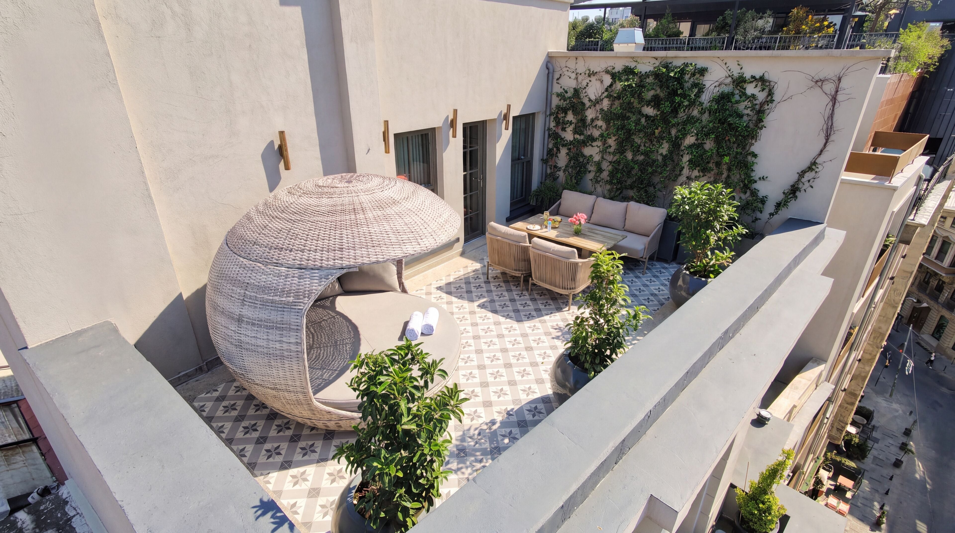 Eine Dachterrasse mit einer runden Sitzecke, einer Sofagruppe und Topfpflanzen.