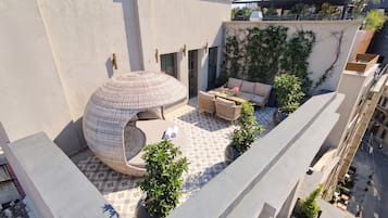 Eine Dachterrasse mit einer runden Sitzecke, einer Sofagruppe und Topfpflanzen.