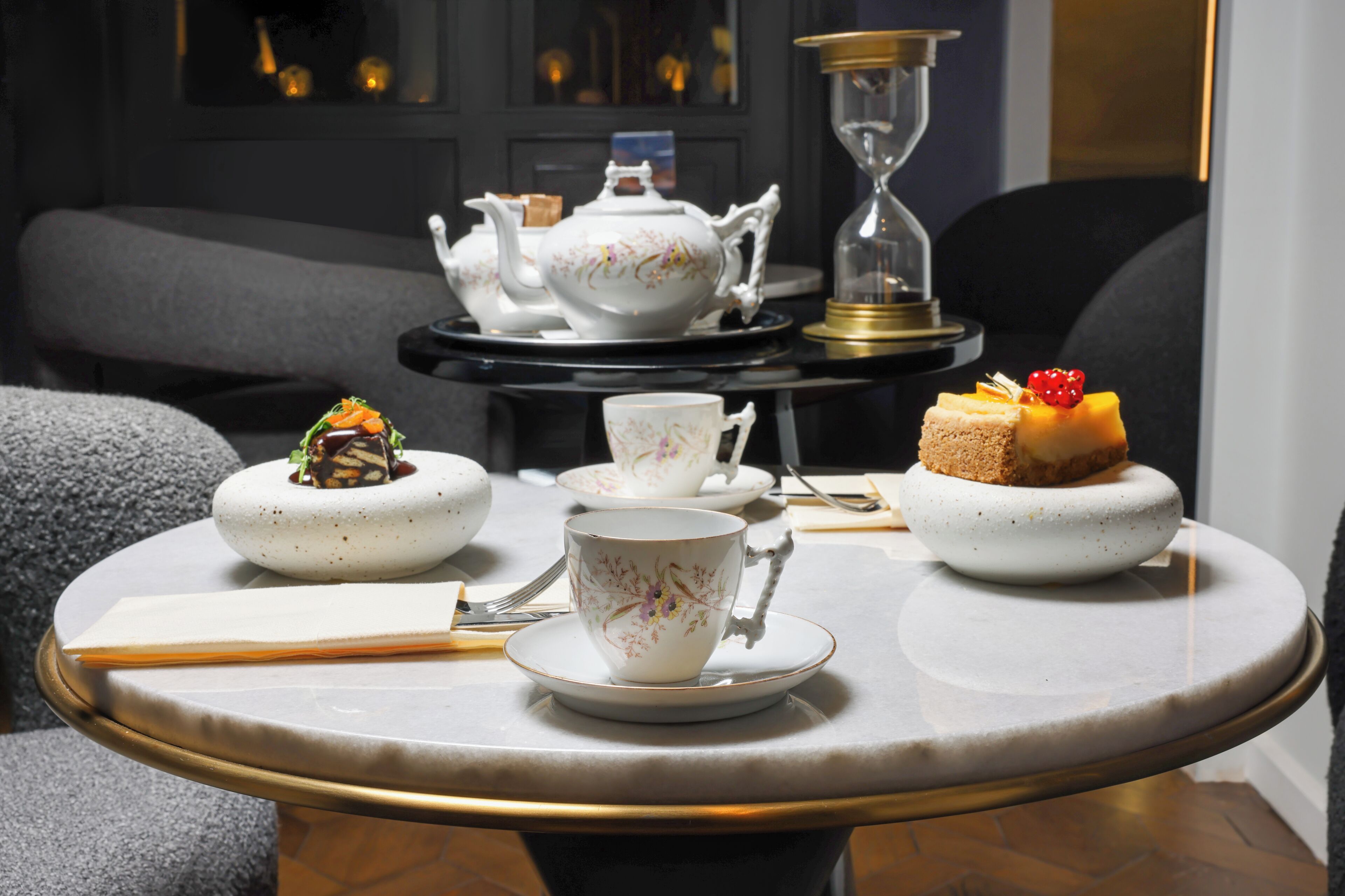 A round table with a tea set, a cup, a fork, and a dessert.
