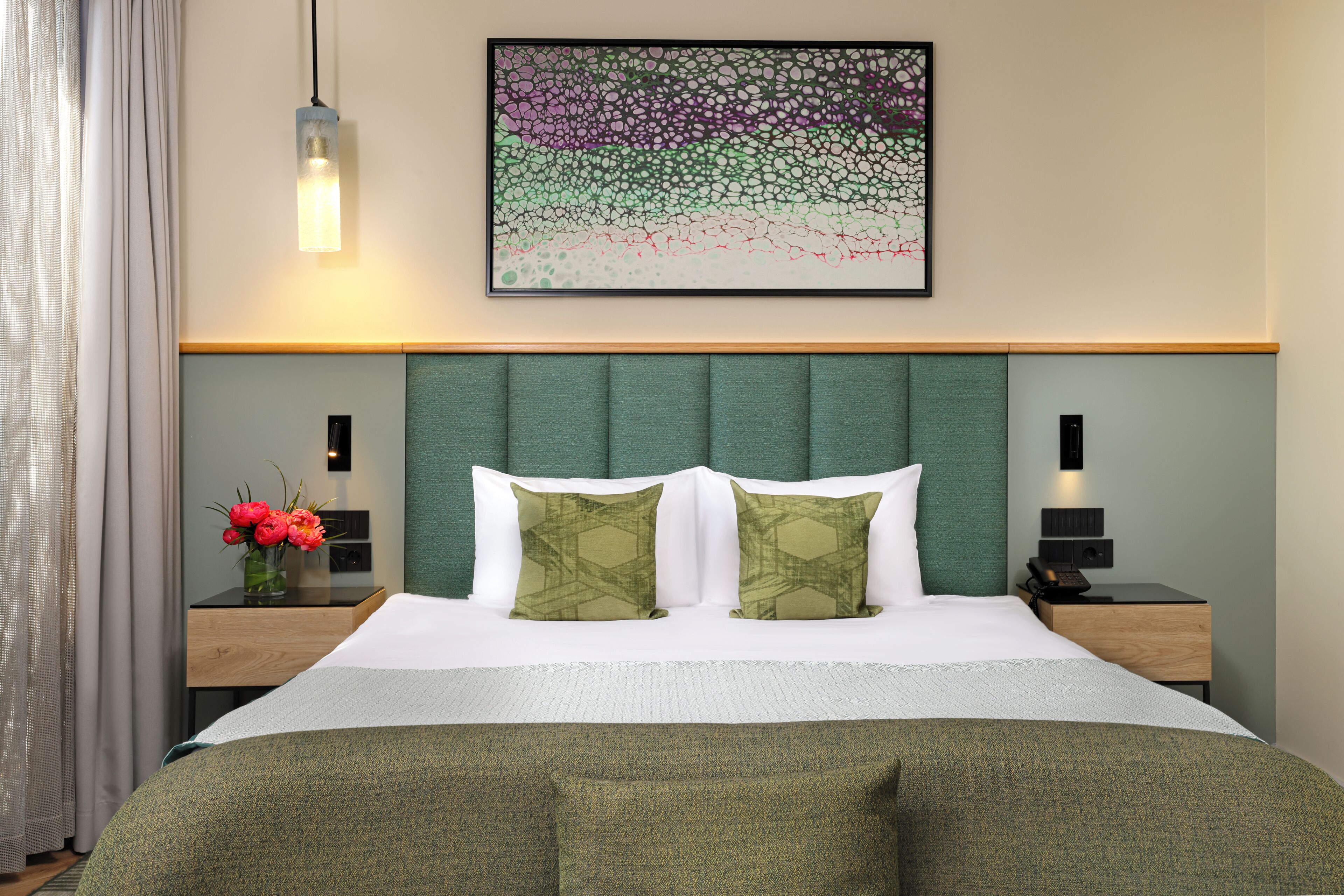 Habitación de hotel con cama, dos mesitas de noche, una obra de arte en la pared y una lámpara de noche.