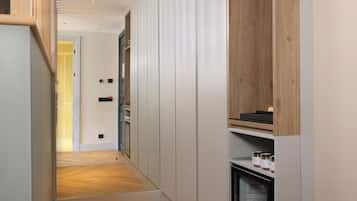 A narrow hallway with a wooden floor, white walls, and a built-in refrigerator on the right.