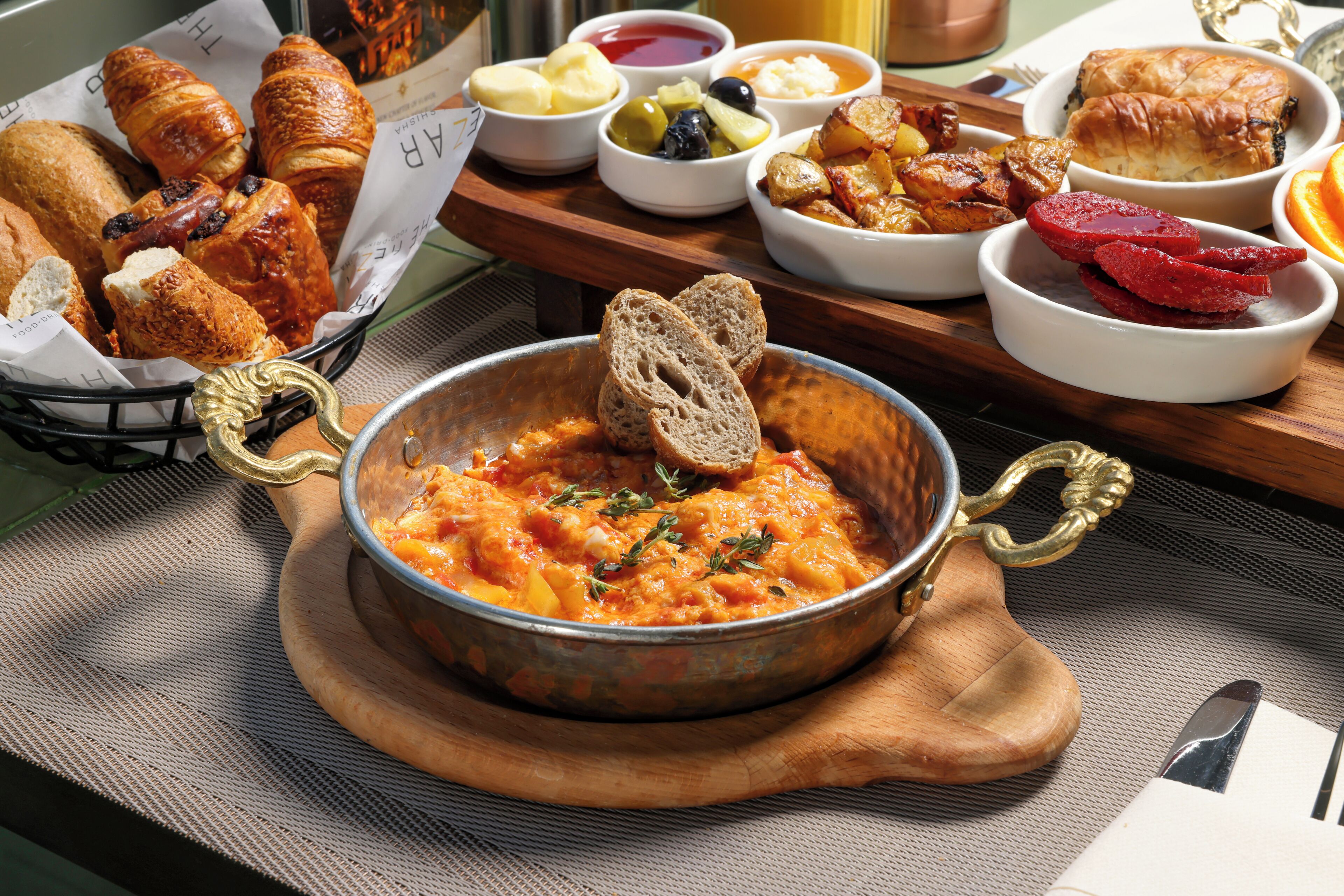 Diverse etenswaren, waaronder brood, gebak en een kom soep, op een houten tafel.