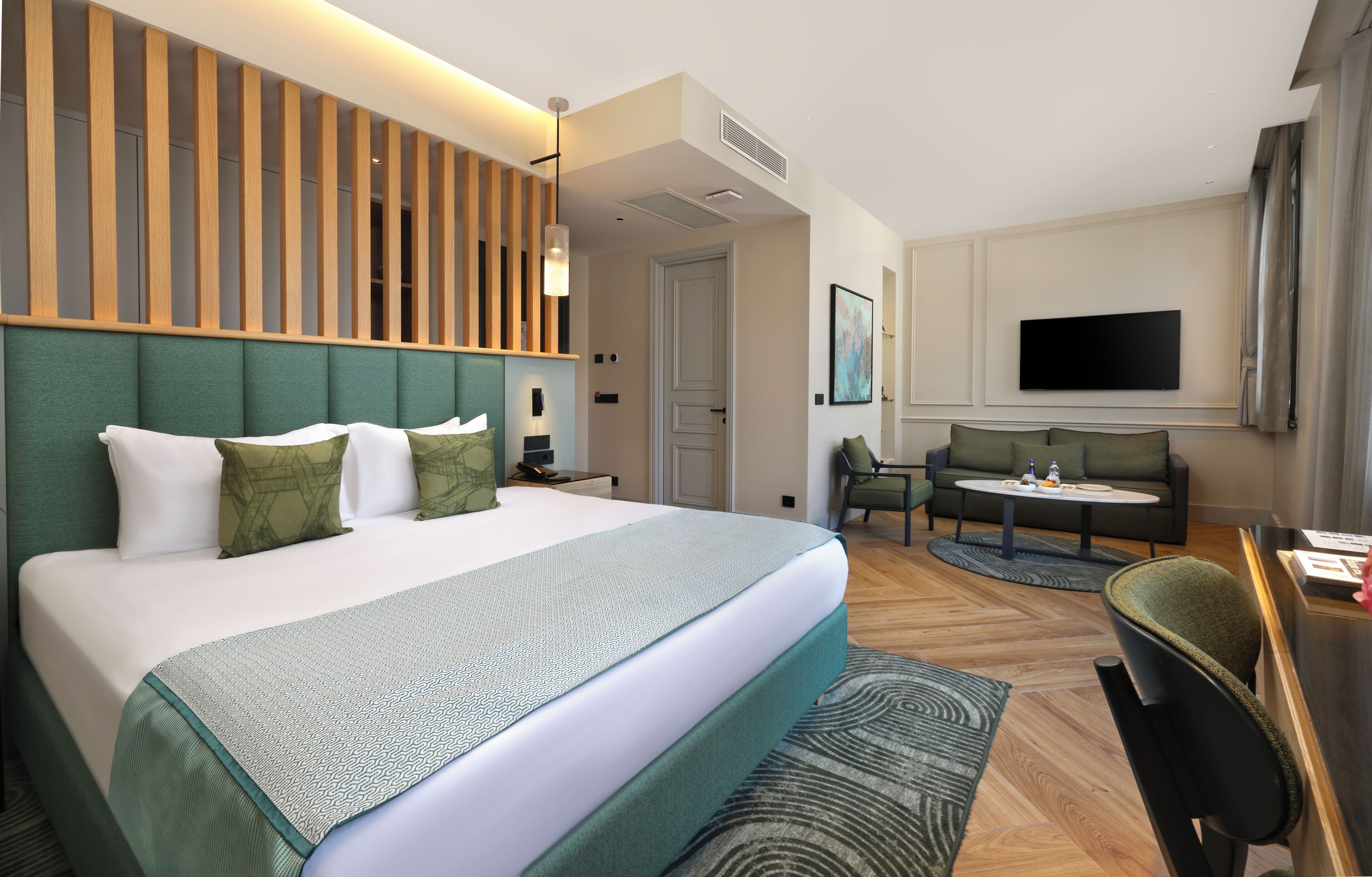 Une chambre d’hôtel avec un grand lit, un bureau, un canapé et une télévision.