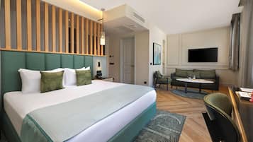 Une chambre d’hôtel avec un grand lit, un bureau, un canapé et une télévision.
