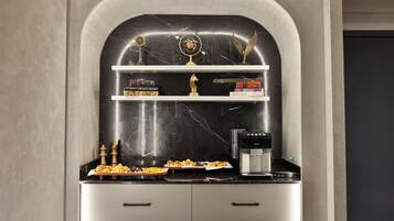 Una cocina con encimeras de mármol, cafetera y objetos decorativos, incluyendo un casco y libros.