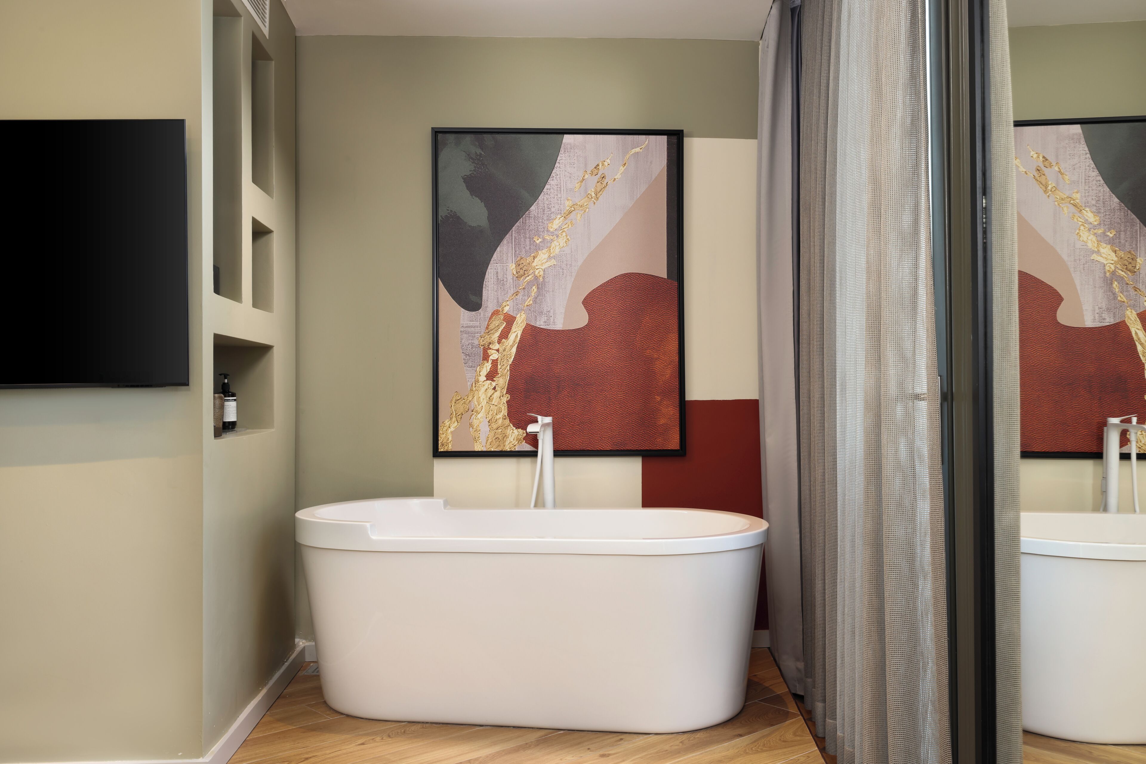 Un baño moderno con una bañera independiente, un espejo grande y un cuadro abstracto contemporáneo en la pared.