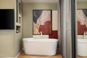 Un baño moderno con una bañera independiente, un espejo grande y un cuadro abstracto contemporáneo en la pared.