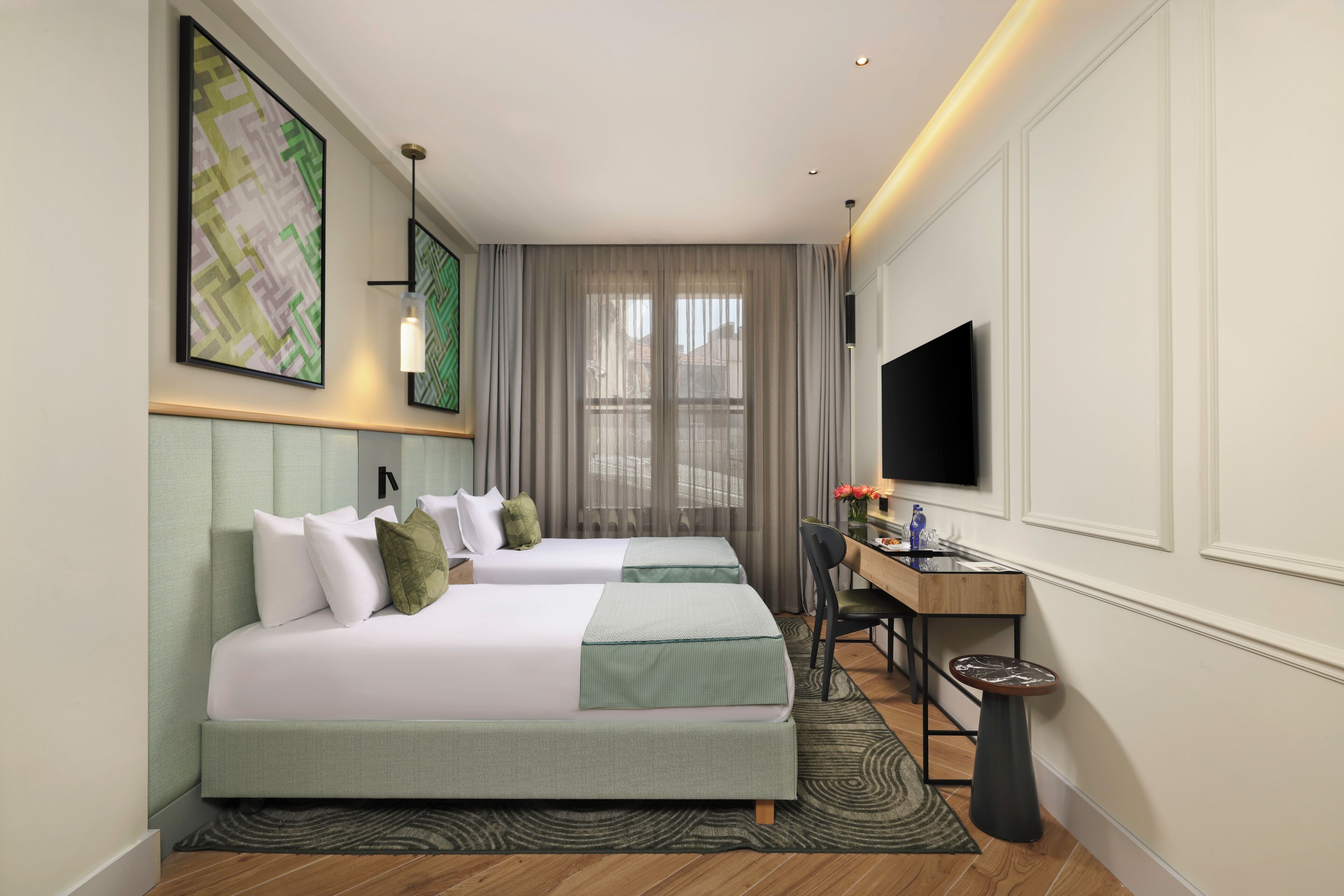 A hotel room with two beds, a desk, a chair, a television, and a window with curtains.