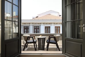 An open balcony with two chairs and a small table, overlooking a building with a tiled roof and white walls. - The Wings Hotels Pera (İstanbul)