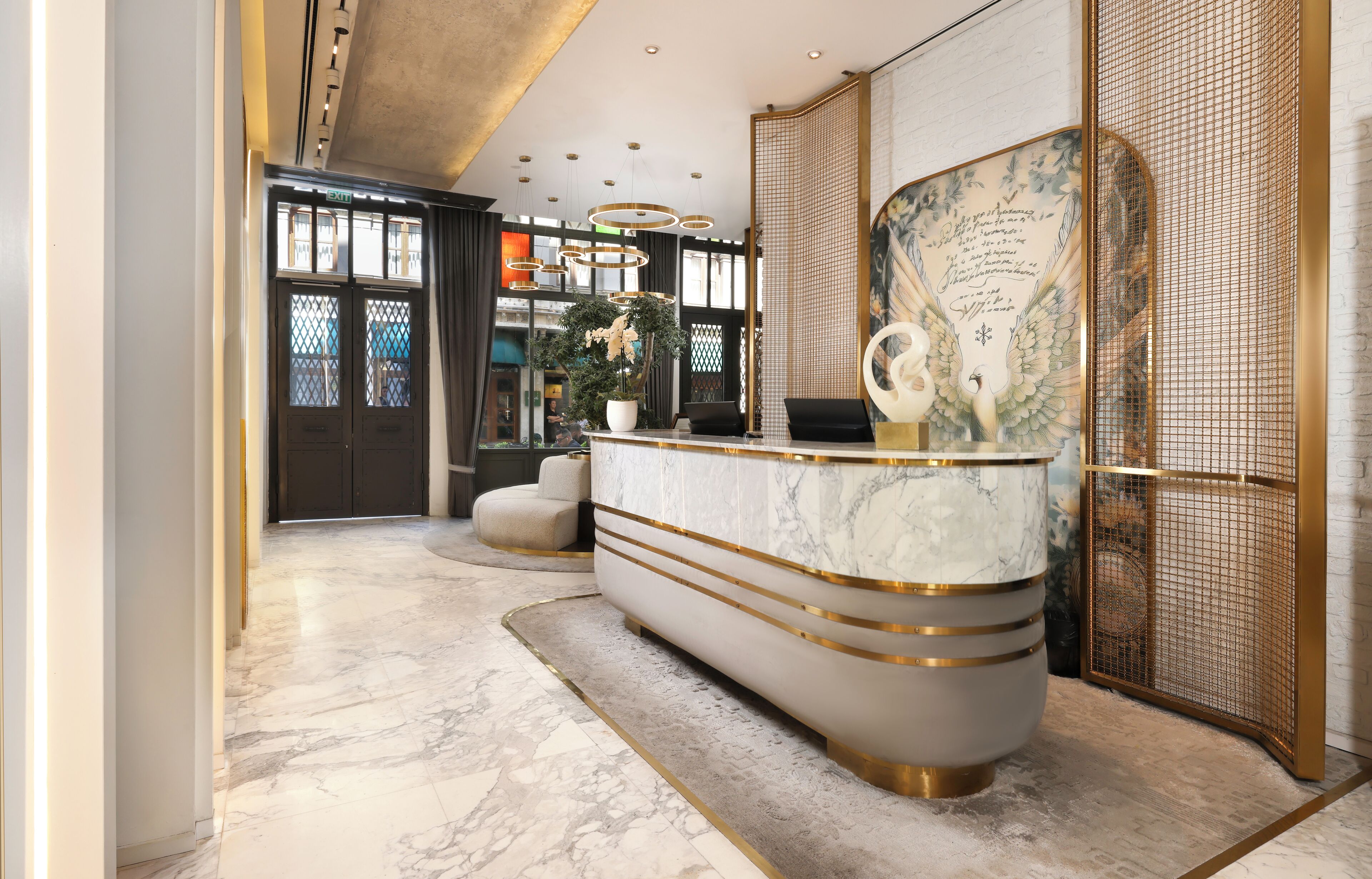 A reception area with a marble counter, a potted plant, and a decorative wall piece.