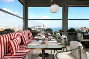 Un espacio para comer en la azotea con vistas a un paisaje urbano, con asientos y mesas a rayas.