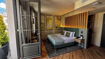 A modern hotel room with a large bed, a wooden headboard, and a sliding glass door leading to an outdoor area.