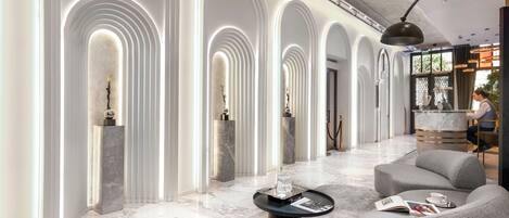 Un vestíbulo moderno con columnas arqueadas, suelo de mármol y mobiliario contemporáneo.
