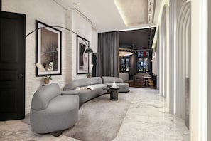 A modern living room with a grey sectional sofa, a coffee table, and a large window with curtains.