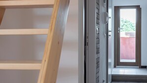 A wooden staircase leading to a landing with a door and a window. - EnJoy Home - Attic with terrace in downtown/hospital area (Padova)