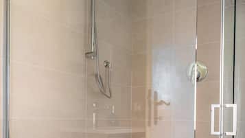 Ducha envuelta en vidrio con cabezal de ducha manual y grifo empotrado.