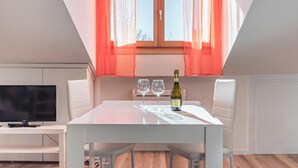 A dining area with a white table, two wine glasses, and a bottle of wine. - EnJoy Home - Attic with terrace in downtown/hospital area (Padova)