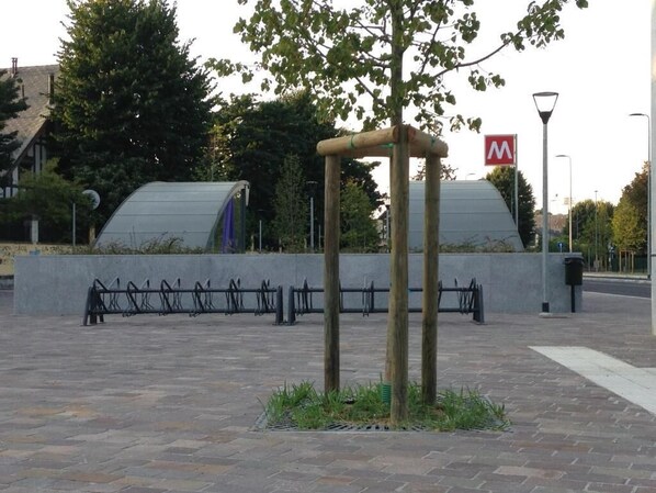 Un espace de repos abrité, délimité par une clôture en métal, avec un petit arbre au centre.