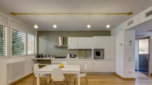 A modern kitchen with white cabinets, a dining table with chairs, and a yellow hanging light fixture. - Facing San Siro Stadium 6 beds 300meters from the metro with garage (Milano)