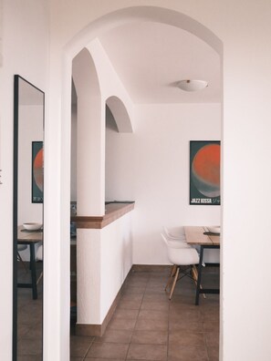 Una cocina moderna con un arco, un comedor con mesa y sillas, y un cartel en la pared.