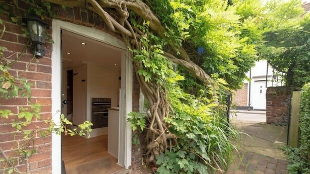 A brick house with a wooden door and a small porch. - Countryside Escape in Beautiful Cosy Cottage (Cobham)