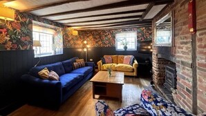 A cozy living room with a blue sofa, a yellow sofa, a wooden coffee table, and a fireplace. - Countryside Escape in Beautiful Cosy Cottage (Cobham)