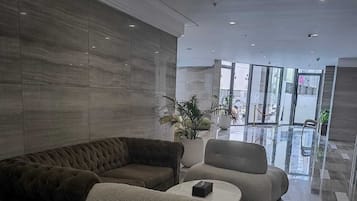 A modern lobby with a sectional sofa, two armchairs, and a coffee table.