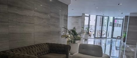 A modern lobby with a sectional sofa, two armchairs, and a coffee table.